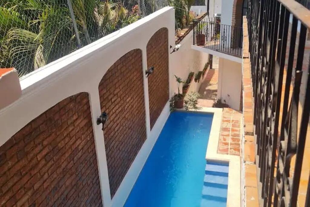 Ein Schwimmbecken mit Backsteinmauer und einem Balkon.