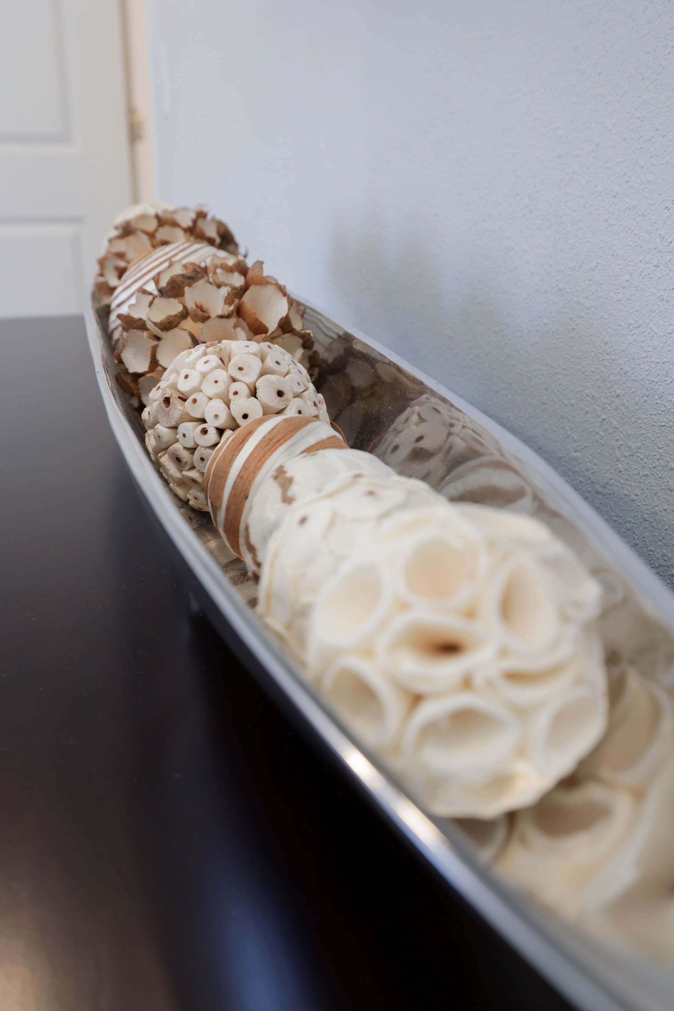 A tray with decorative items, including a white spherical object with a textured surface and a patterned object with a brown and white striped band.