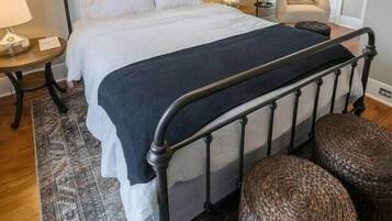 Una camera da letto con un letto, comodini, una sedia, una ventola a soffitto e un tappeto decorato.