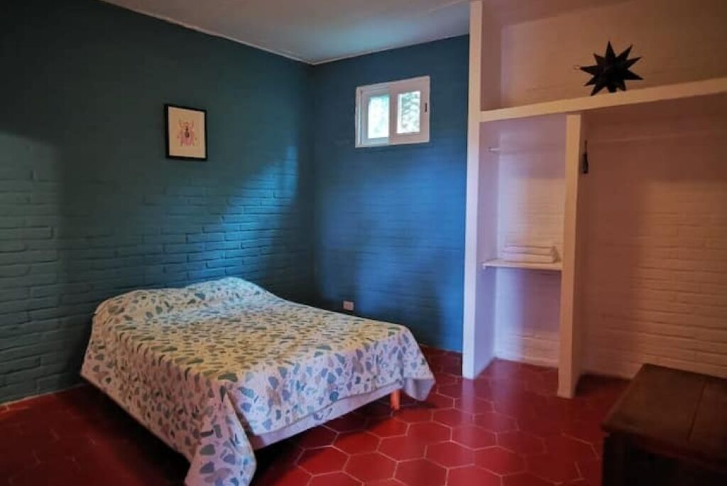 Ein Schlafzimmer mit einem Bett, einem Fenster und einem weißen Regal.