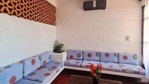 Ein Sitzbereich mit weißer Backsteinwand, einer Wand mit geometrischem Muster und einem blauen Sofa mit runden Kissen.