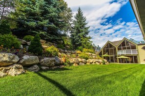 A well-maintained lawn, a stone retaining wall, and a building with a balcony and large windows. - 2 bedroom Ski Condo 4; Sleeps 6, Near Slopes; Feb. 5-12, 2027 (Park City)