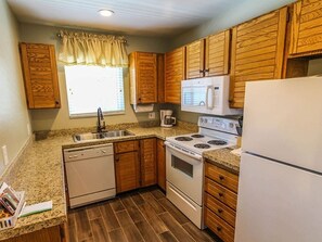 A compact kitchen with wooden cabinets, a built-in microwave, a stove, and a dishwasher. - 2 bedroom Ski Condo 4; Sleeps 6, Near Slopes; Feb. 5-12, 2027 (Park City)