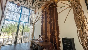 Una habitación con un amplio ventanal, una mesa de madera y una persona trabajando en un escritorio.