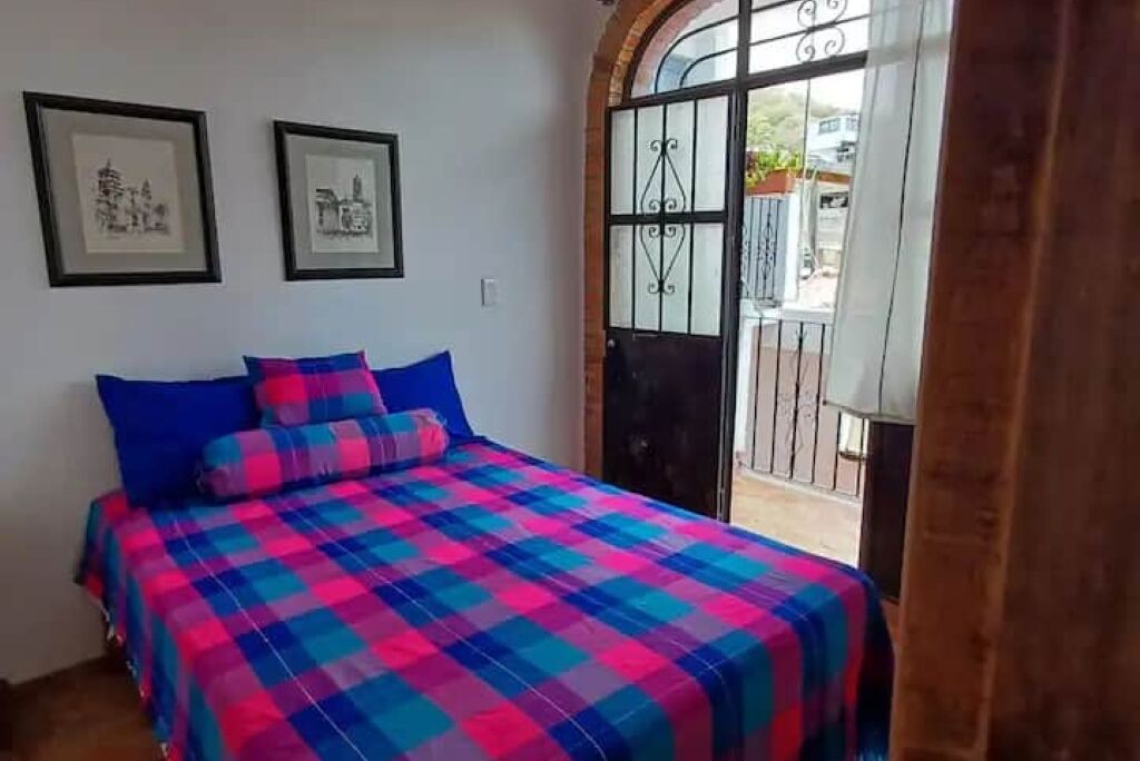 Una camera da letto con un letto, due quadri appesi al muro e una porta con cancello in metallo.