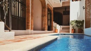En swimmingpool med ett kaklat poolområde, murade väggar och en grind av metall.