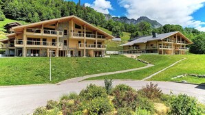 A two-story chalet with balconies, set in a mountainous area with a clear sky. - Apartment in Alps With Pool and Jacuzzi (Abondance)