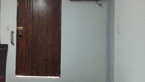 Une pièce dotée d’une porte en bois, d’un climatiseur et d’un téléviseur fixé au mur.