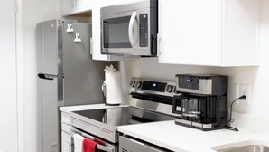 Une cuisine moderne dotée d’appareils électroménagers en acier inoxydable, de meubles blancs et d’un lave-vaisselle.