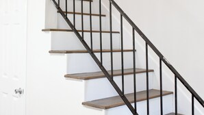 Un escalier avec des marches en bois et des rampes en métal noir.