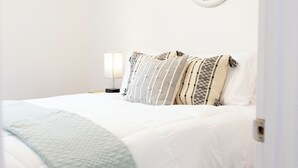 Une chambre à coucher comprenant un lit, un ventilateur de plafond, une assiette décorative fixée au mur et une table de chevet avec une lampe.
