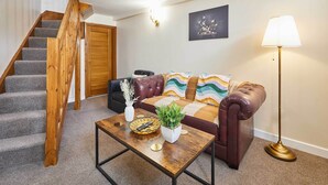 Ein Wohnzimmer mit Treppe, Sofa, Couchtisch, Lampe und einem Bild an der Wand.