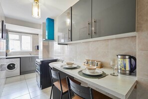A modern kitchen with a large island, stainless steel appliances, and a coffee maker. - Host Stay The Annex (Smethwick)