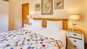 A double bed with a colorful quilt, a wooden headboard, bedside tables with lamps, and framed artwork on the wall. - Host Stay The Station Cottage (Rowlands Gill)