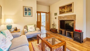 A cozy living room with a fireplace, a sofa, a coffee table, and a TV. - Host Stay The Station Cottage (Rowlands Gill)