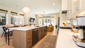 A modern kitchen with a large island, wooden cabinets, and a built-in dishwasher.