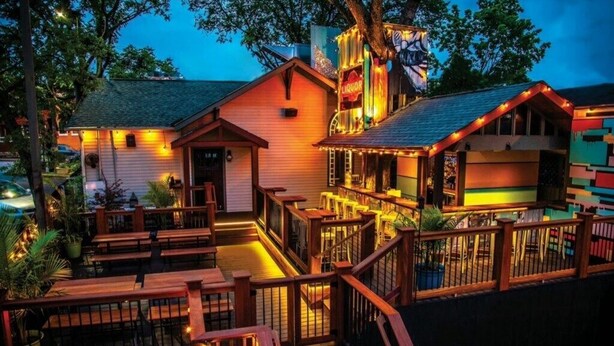 A building with a porch, wooden railings, and a sign that reads 'Liquor.'