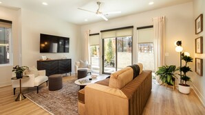 A modern living room with a sofa, armchair, coffee table, and TV.