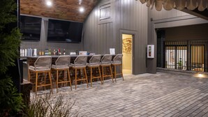A bar area with a wooden ceiling, bar stools, and a brick wall.
