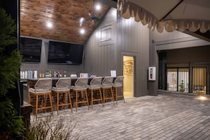 Eine Bar mit Holzbalkendecke, Barhocker und einer Ziegelwand.