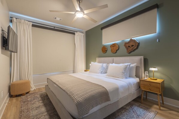 A bedroom with a bed, bedside tables, a ceiling fan, and wall-mounted decor.