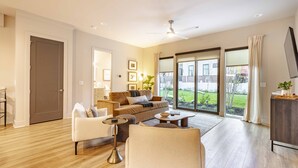 A spacious living room with a sofa, chairs, a coffee table, and a television. - Unit 11 I Noa Nashville | 4BR Luxury Retreat + Resort Pool (Nashville)