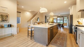 A modern kitchen with a central island, pendant lighting, and a view to the dining area. - Unit 11 I Noa Nashville | 4BR Luxury Retreat + Resort Pool (Nashville)