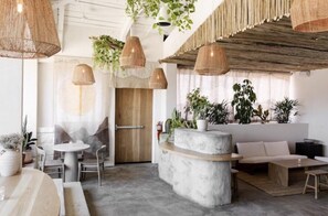 A modern interior with a round table, seating area, and hanging plants.