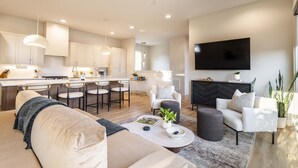 A modern living room with a sofa, coffee table, and a TV mounted on the wall.