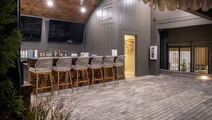 A bar area with a wooden ceiling, bar stools, and a brick wall.
