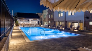 An outdoor swimming pool with lounge chairs and a covered seating area.