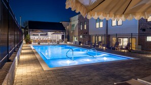 Piscina exterior con sillones de descanso y zona de estar cubierta.
