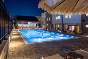 An outdoor swimming pool with lounge chairs and a covered seating area.