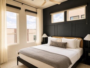 A bedroom with a bed, two bedside tables, a window, and a ceiling fan.