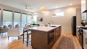 Una cocina moderna con una isla grande, piso de madera y vista al área de estar.