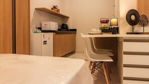 Une cuisine compacte équipée d’un réfrigérateur, d’un four à micro-ondes et d’une étagère où sont disposées des plantes en pot.