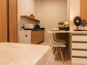 A compact kitchen with a refrigerator, microwave, and a shelf with potted plants. - HN Pariquis (Belém)