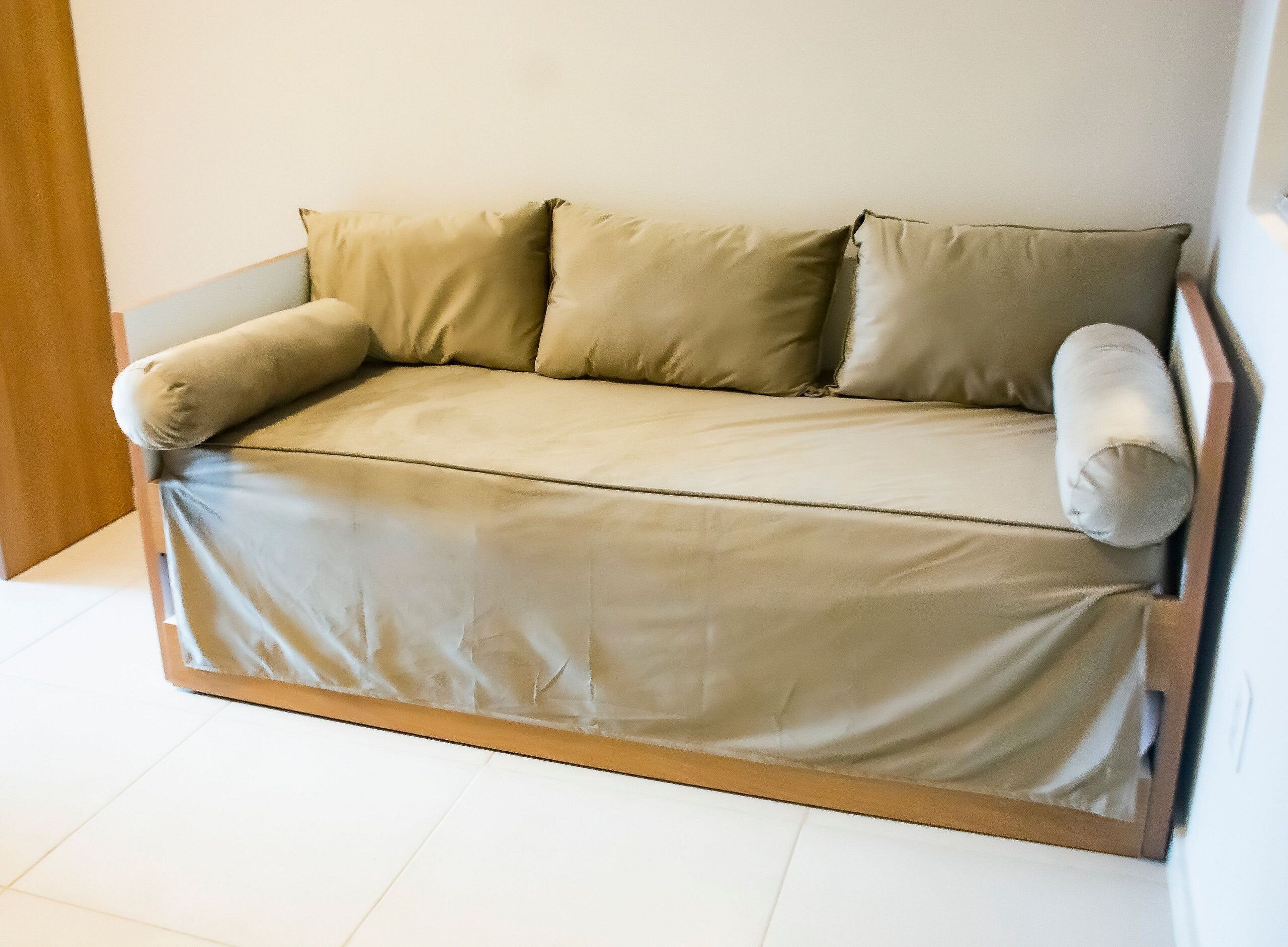 A sofa with a wooden frame and a light-colored fabric cover.