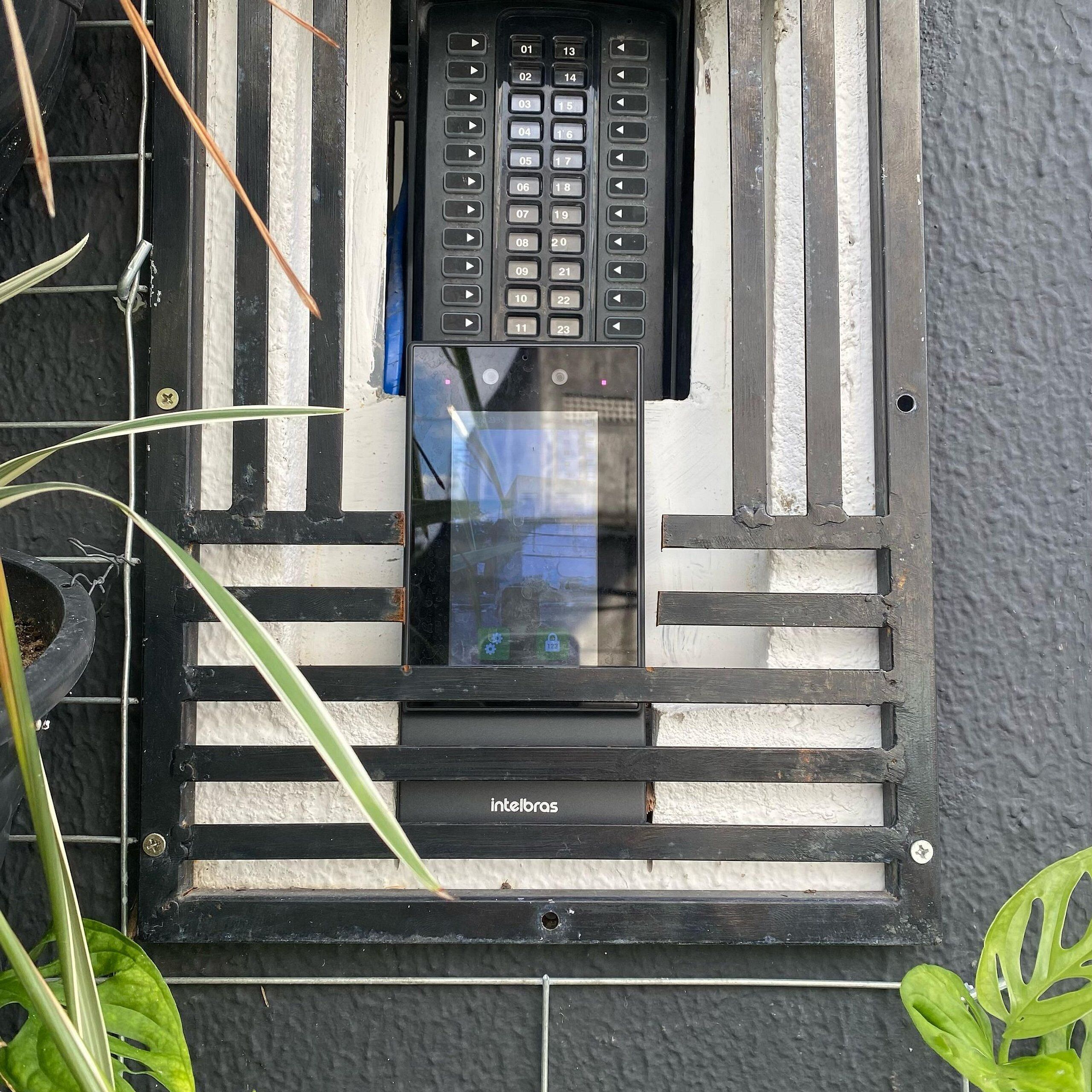 Una ventana con un teclado de seguridad y un pequeño macetero con una planta.