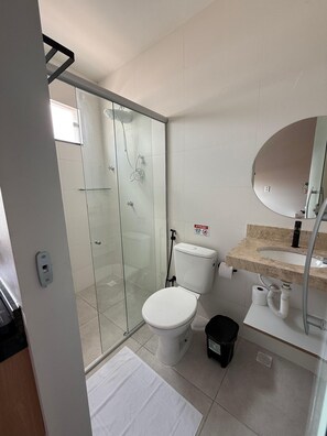 A modern bathroom with a glass shower enclosure, a toilet, a sink with a marble countertop, and a mirror. - HN Pariquis (Belém)