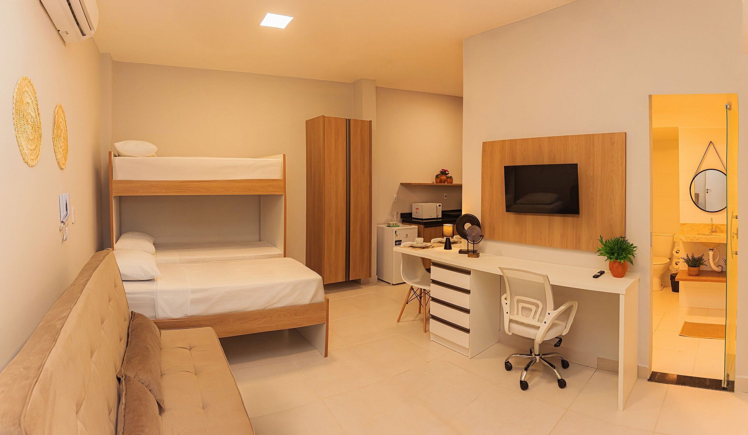 Habitación compacta con literas, un escritorio con silla, una kitchenette pequeña y un baño.