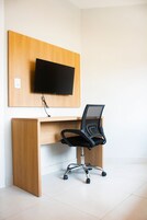 Un espacio de oficina moderno con un escritorio de madera, una silla de oficina negra y un televisor de pantalla plana montado.