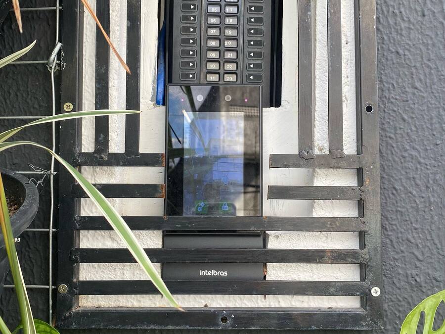 A window with a security keypad and a small window box with a plant.