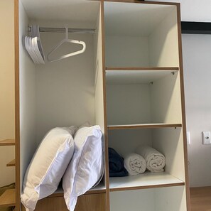 A wardrobe with two shelves, one with rolled towels and the other with hanging clothes. - HN Pariquis (Belém)