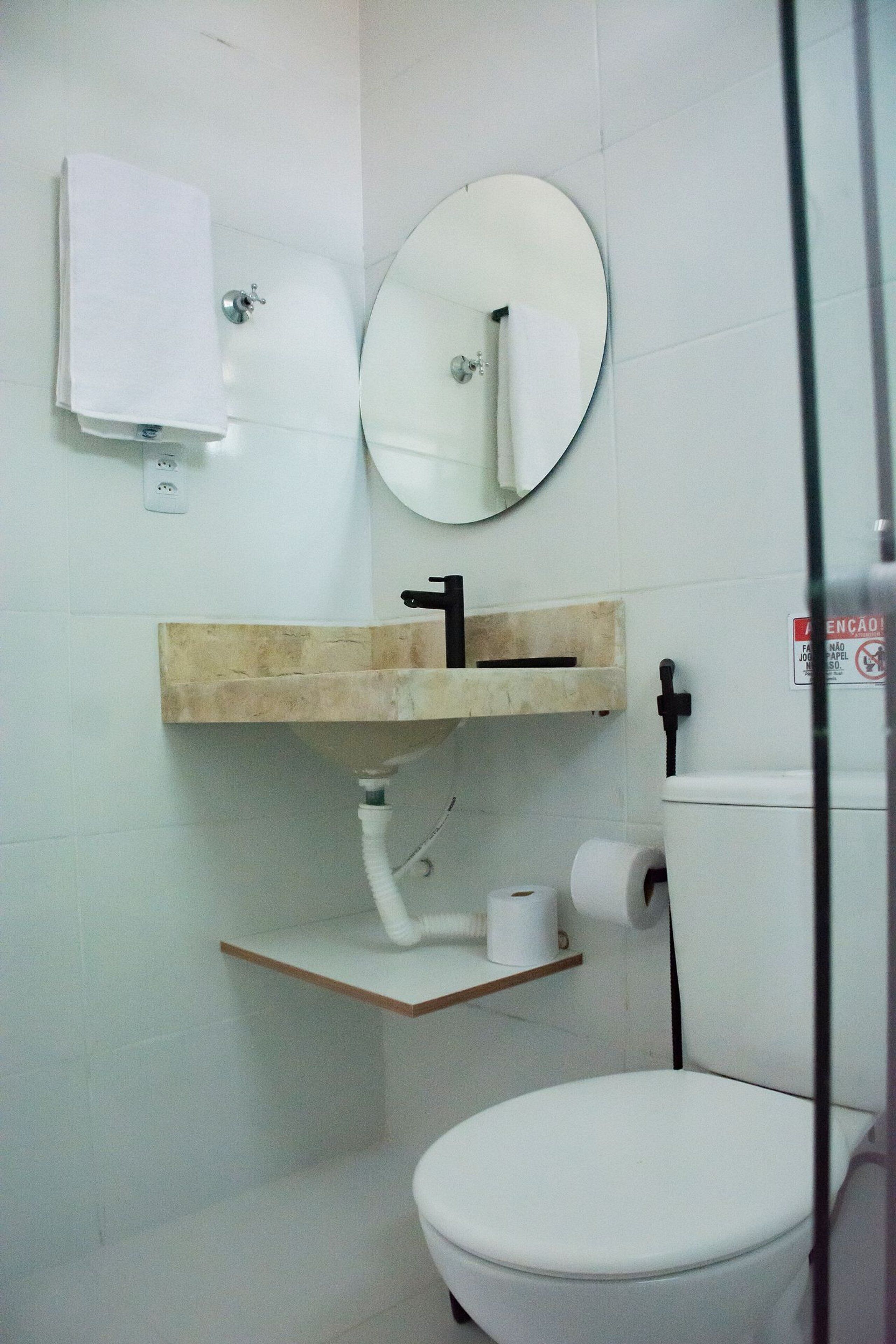 A small bathroom with a toilet, a sink with a mirror above it, and a towel hanging on the wall.