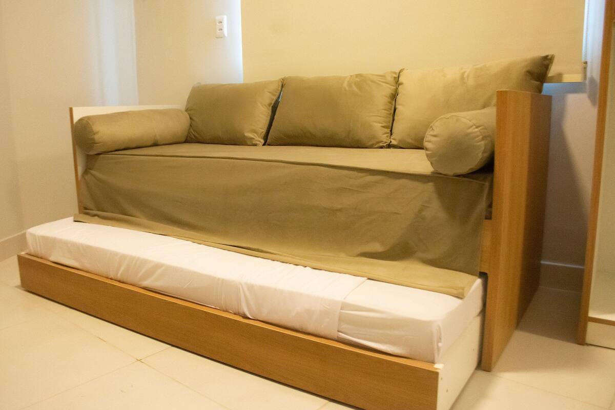 A convertible sofa bed with a wooden frame and a white mattress.