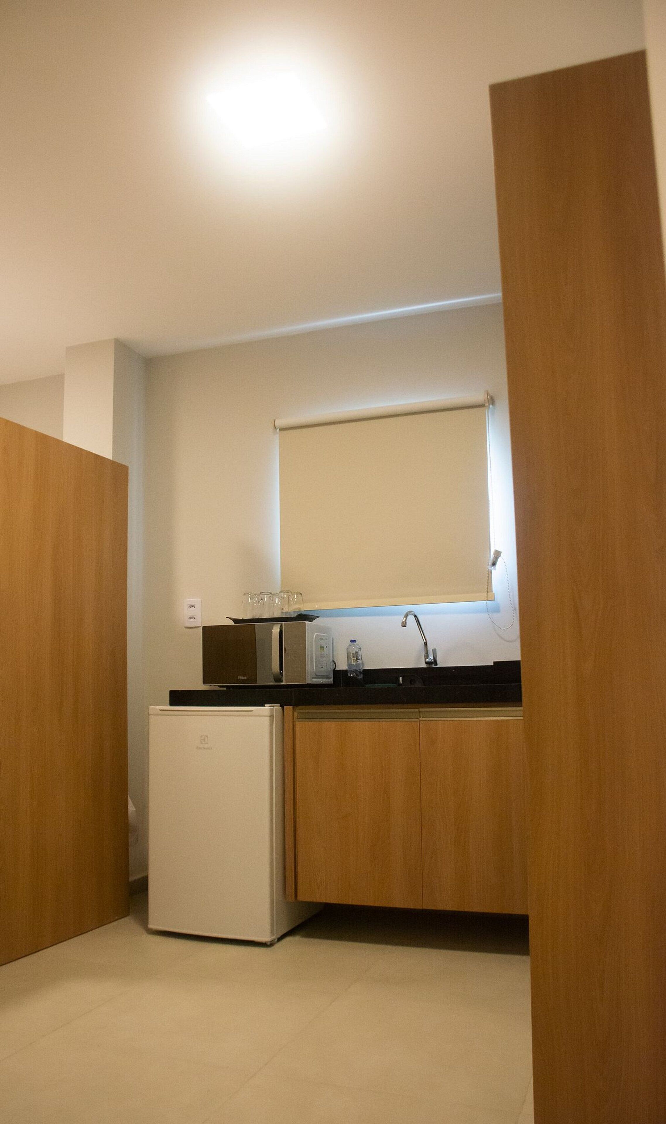 Uma cozinha compacta com geladeira, micro-ondas e pia.