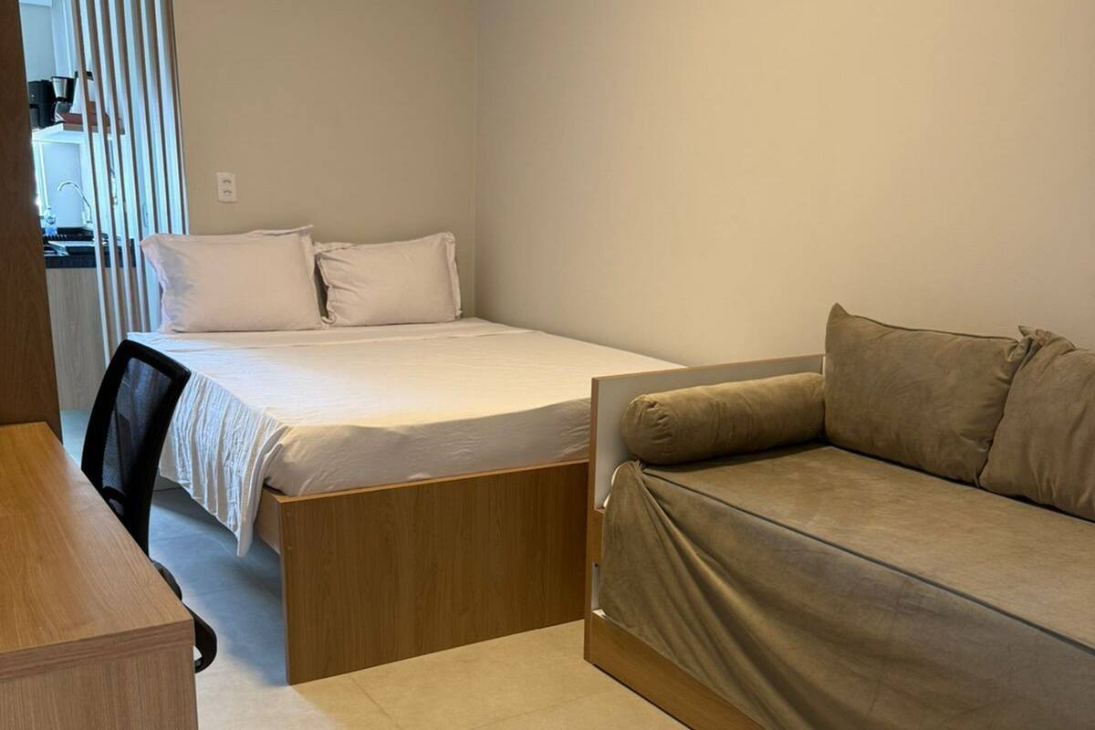 A compact bedroom with a bed, a sofa, and a desk.