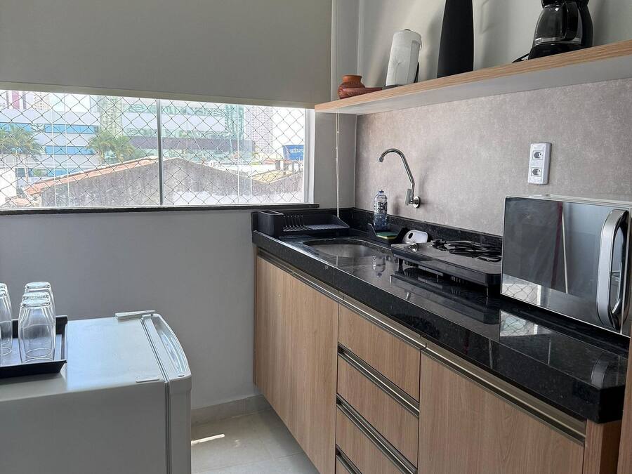 A modern kitchen with a black countertop, wooden cabinets, a stainless steel sink, and a window with a view of buildings.