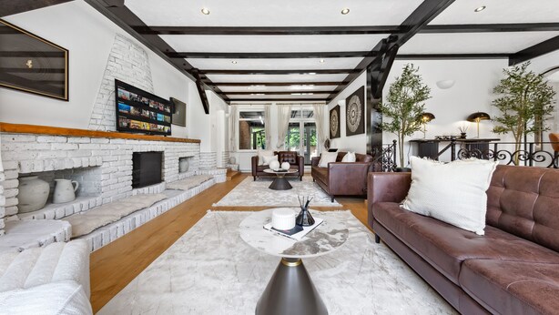 A spacious living room with a fireplace, a brown leather sofa, and a coffee table.
